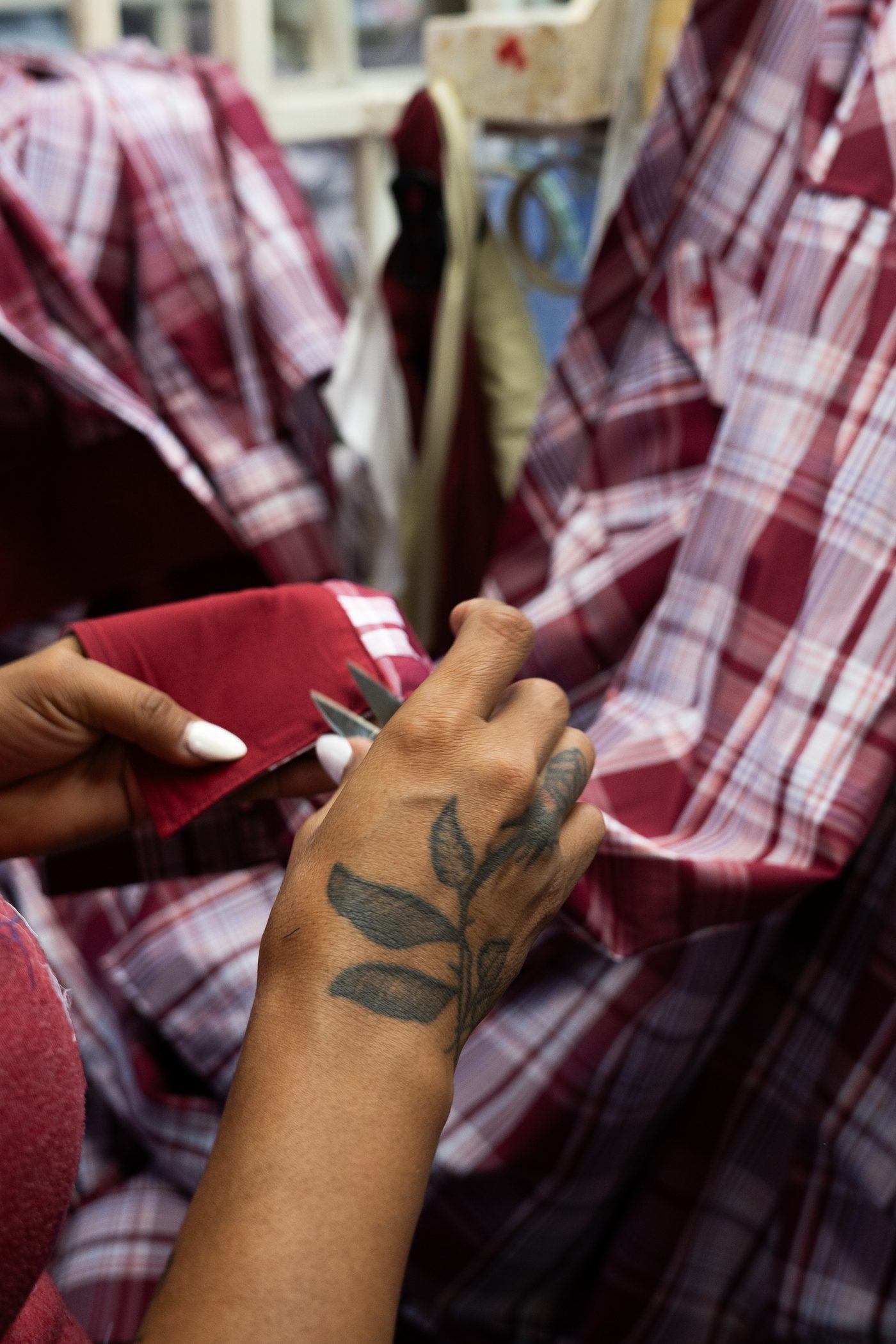 Hand-finishing and thread trimming on plaid casual shirts at Manchester's apparel factory