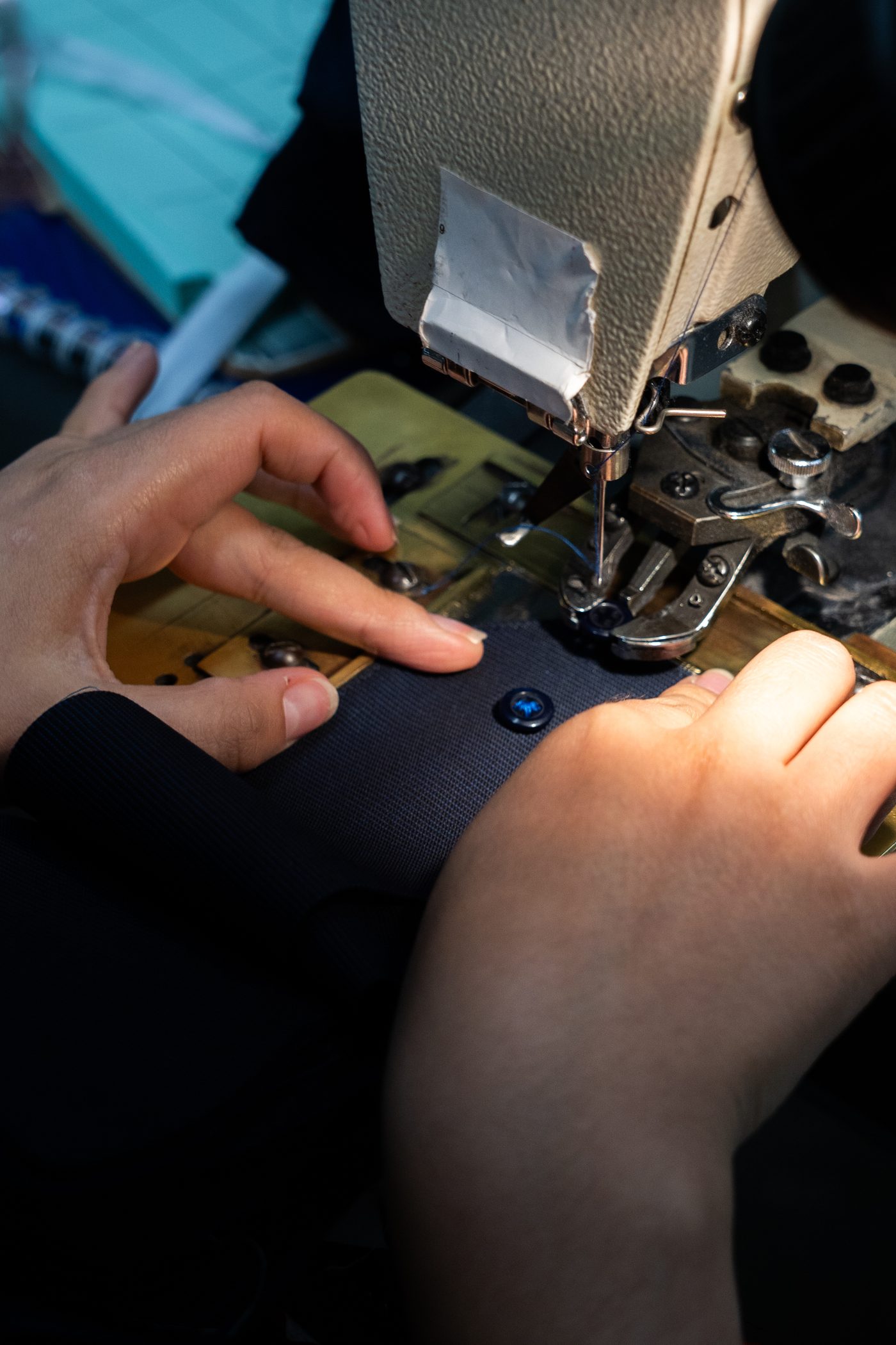 Automated button-attaching machine sewing buttons onto a navy dress shirt cuff